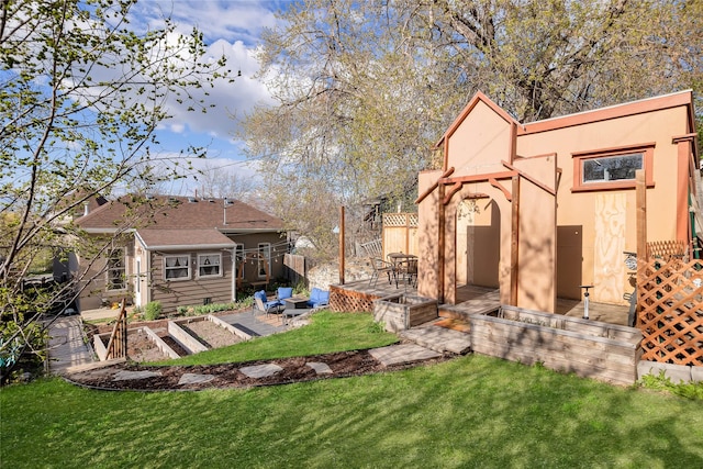 exterior space featuring fence, stucco siding, a vegetable garden, a patio, and a yard