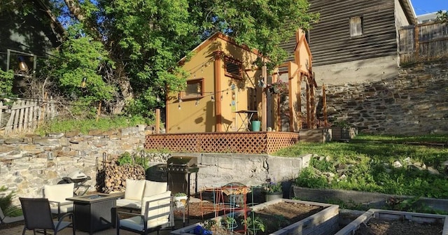 view of patio featuring an outdoor fire pit, fence, a vegetable garden, and grilling area
