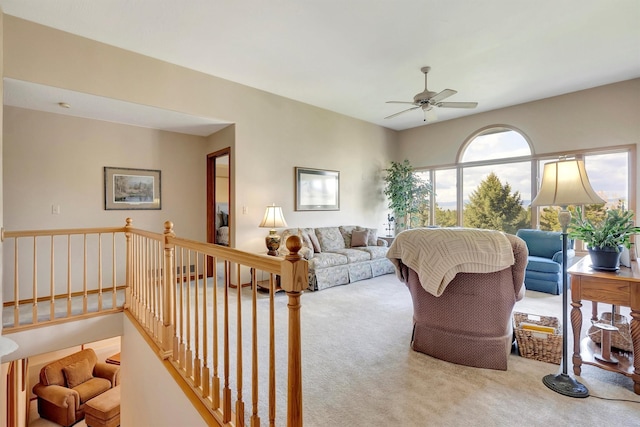 living area with a ceiling fan and carpet