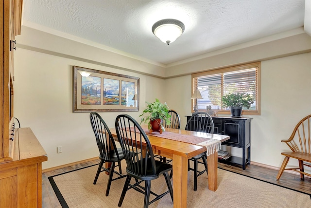 dining room with a textured ceiling, baseboards, and light wood-style flooring