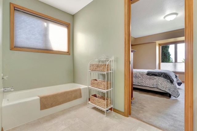 ensuite bathroom featuring baseboards, a bath, and connected bathroom