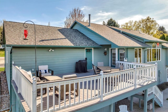 back of property with a deck, a shingled roof, and outdoor dining area