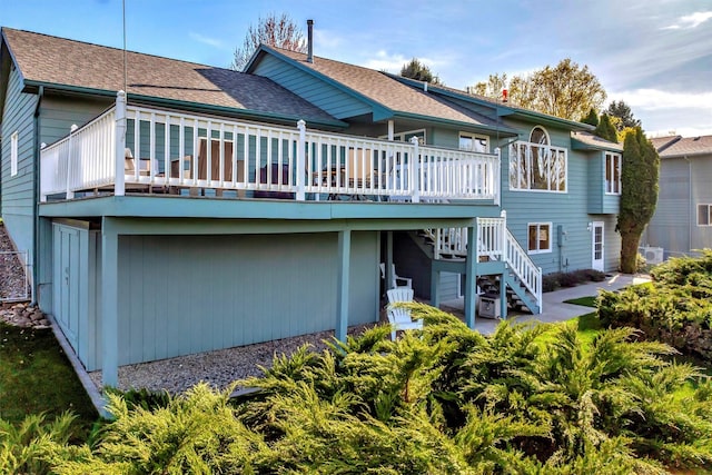 rear view of property featuring a wooden deck, a shingled roof, and stairs