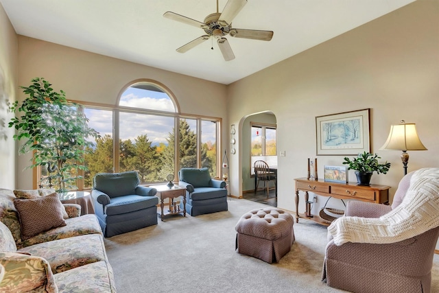 living room with arched walkways, ceiling fan, and carpet