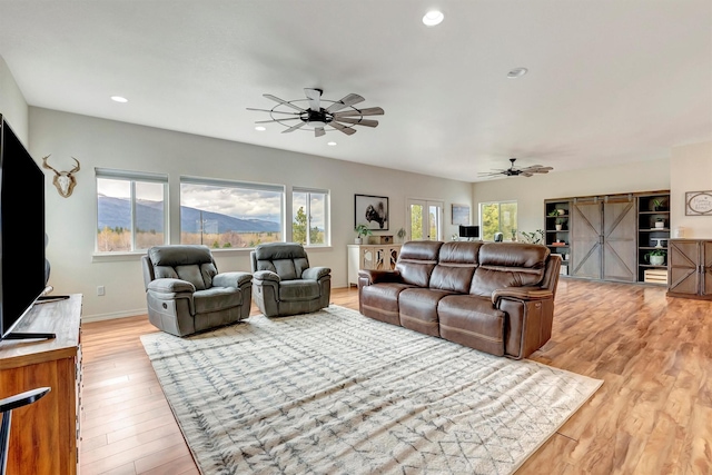 living area featuring light wood-type flooring, a ceiling fan, baseboards, and recessed lighting