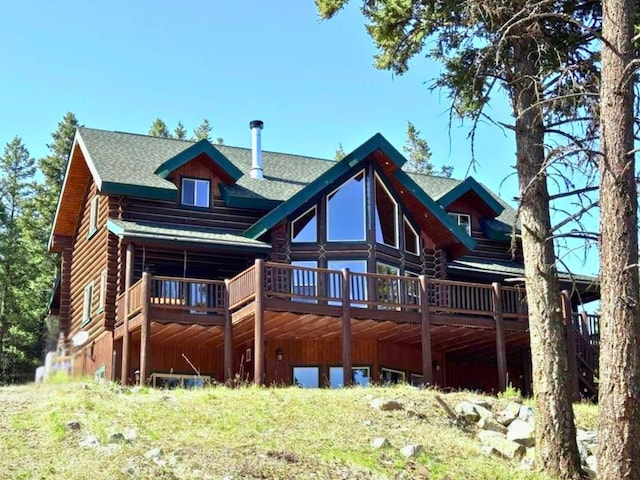 back of house with roof with shingles, log exterior, and a deck