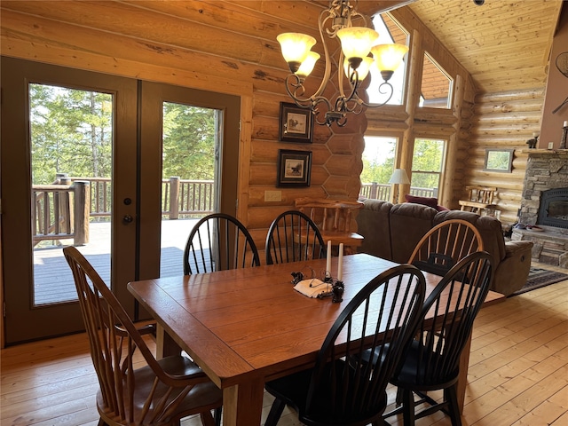 dining room with log walls, a fireplace, light wood-style flooring, and a chandelier