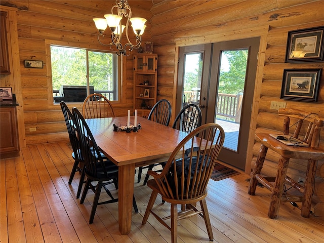 dining area featuring french doors, light wood-style flooring, rustic walls, and a notable chandelier