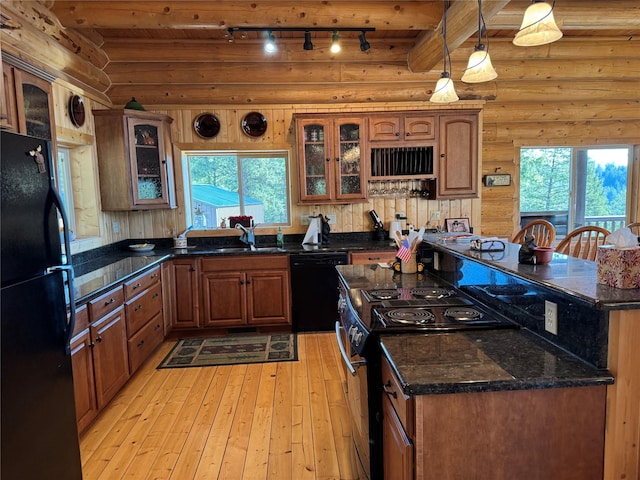 kitchen featuring a kitchen island, rail lighting, black appliances, log walls, and light wood-style flooring