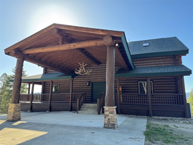 log-style house featuring log siding and a shingled roof