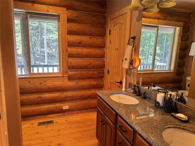 full bathroom with a sink, log walls, plenty of natural light, and hardwood / wood-style floors