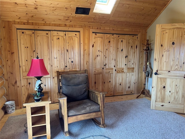 sitting room with lofted ceiling with skylight, wooden walls, and wooden ceiling