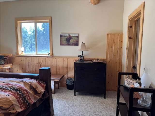 bedroom with wooden walls, a wainscoted wall, and light carpet
