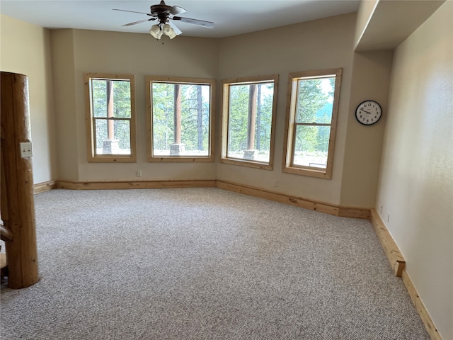 carpeted empty room with baseboards, ceiling fan, and a wealth of natural light