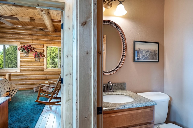 550 Jackson Meadows Rd, Kila, MT 59920 - half bath with log walls, wooden ceiling, beamed ceiling, vanity, and toilet