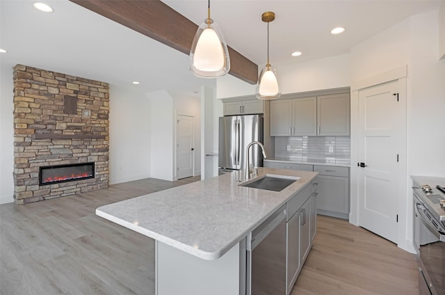 kitchen featuring decorative backsplash, light wood-type flooring, a sink, appliances with stainless steel finishes, and gray cabinetry