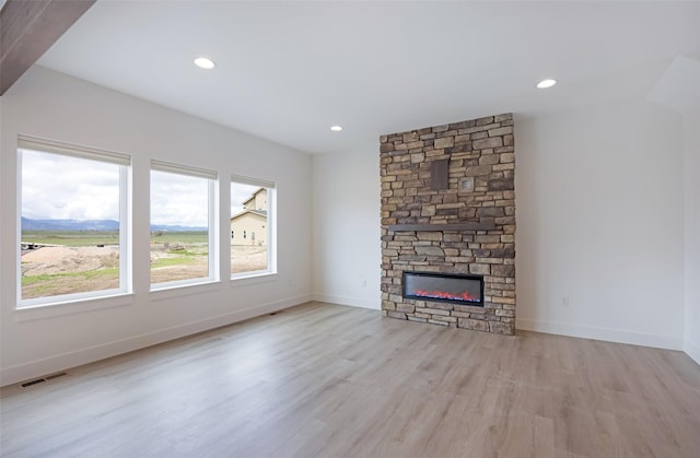 unfurnished living room with visible vents, baseboards, wood finished floors, and a fireplace