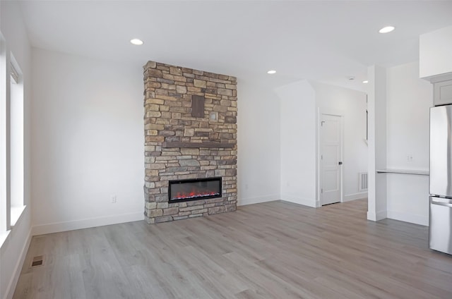 unfurnished living room with visible vents, a fireplace, baseboards, light wood finished floors, and recessed lighting