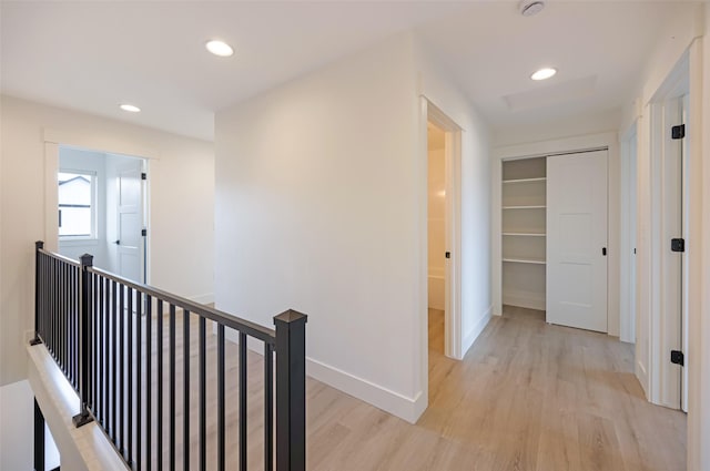 hallway featuring recessed lighting, light wood-style flooring, baseboards, and an upstairs landing