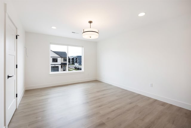 spare room with recessed lighting, light wood finished floors, and baseboards