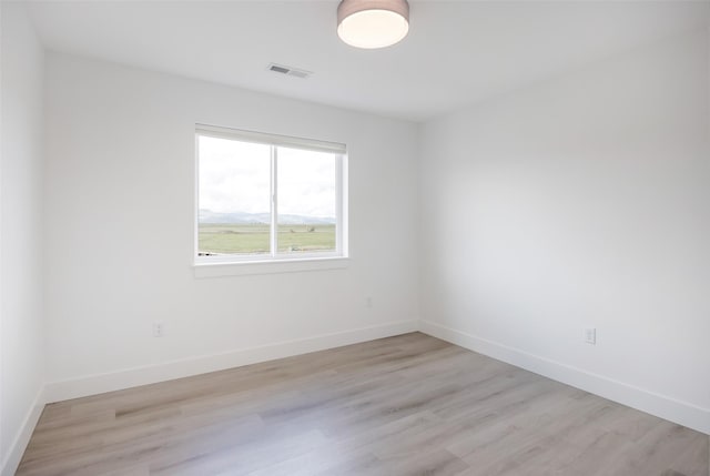 empty room featuring baseboards, light wood-style flooring, and visible vents