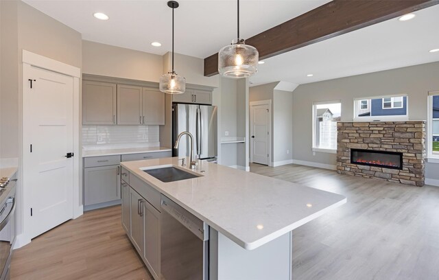 kitchen featuring stainless steel appliances, gray cabinetry, a sink, and light wood finished floors