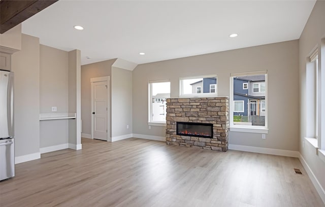 unfurnished living room with a stone fireplace, light wood-style flooring, recessed lighting, baseboards, and visible vents