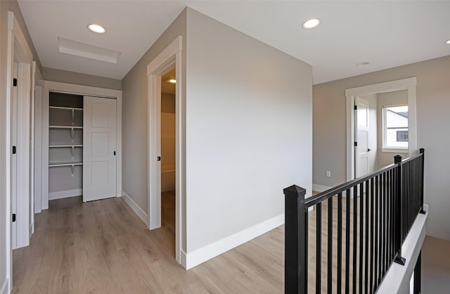 hallway with recessed lighting, baseboards, an upstairs landing, and light wood-style floors