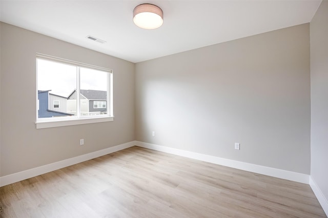 spare room featuring light wood-type flooring, baseboards, and visible vents
