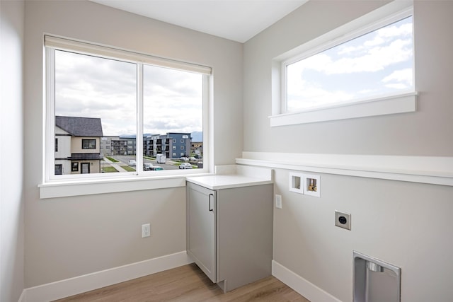 laundry area featuring electric dryer hookup, baseboards, laundry area, and light wood-type flooring