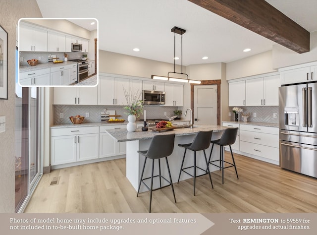 kitchen with light wood-style floors, white cabinets, tasteful backsplash, and stainless steel appliances