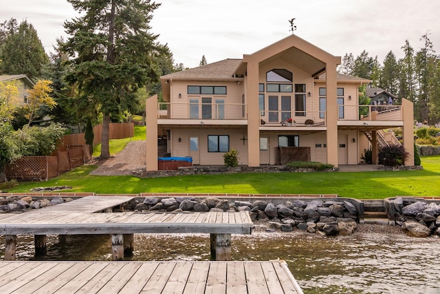 back of property with a lawn, a water view, and fence