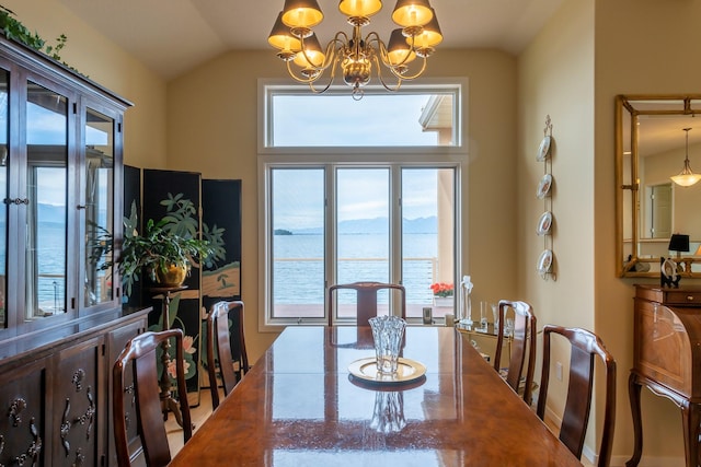 dining area with a water view, an inviting chandelier, and lofted ceiling