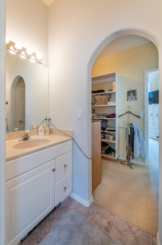 bathroom with tile patterned floors, a spacious closet, and vanity