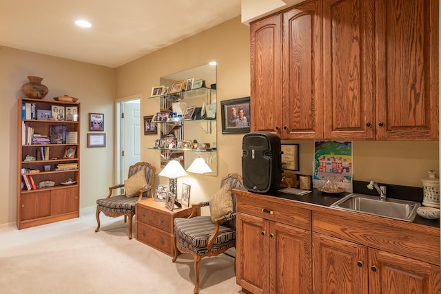 interior space with brown cabinetry, light colored carpet, dark countertops, a sink, and recessed lighting