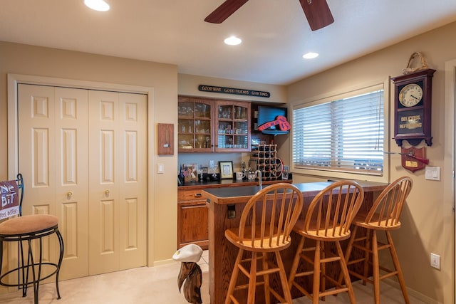 bar featuring light colored carpet, a ceiling fan, baseboards, recessed lighting, and a bar