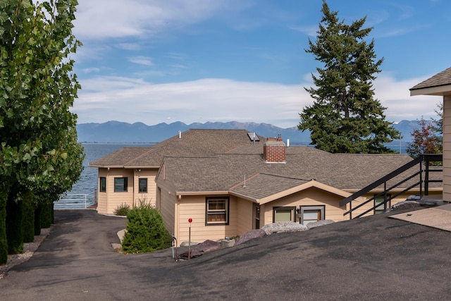 view of front of house with a mountain view, a shingled roof, and a chimney