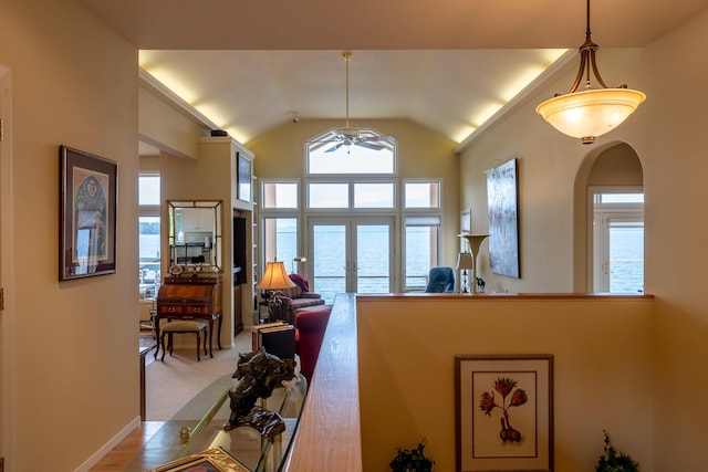 living area with arched walkways, ceiling fan, and vaulted ceiling