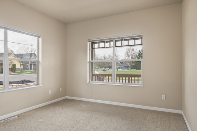 carpeted spare room featuring baseboards and visible vents