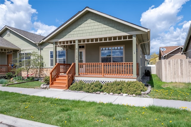bungalow-style house featuring a front lawn, fence, and covered porch