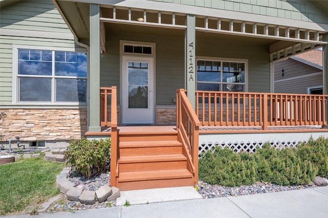 entrance to property with a porch and stone siding