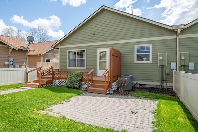 back of property featuring fence, a wooden deck, a patio, central air condition unit, and a yard