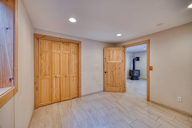 unfurnished bedroom with a wood stove, baseboards, and recessed lighting