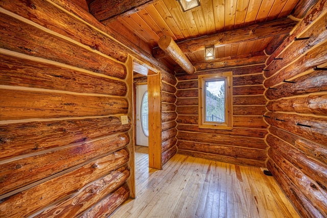empty room featuring beam ceiling, wooden ceiling, and hardwood / wood-style flooring