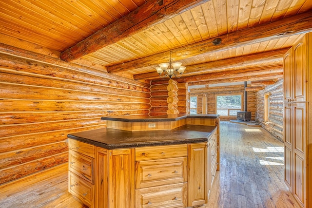 interior space with a wood stove, light wood-style floors, a notable chandelier, dark countertops, and rustic walls
