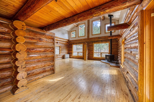 unfurnished living room featuring wooden ceiling, lofted ceiling with beams, log walls, wood-type flooring, and a wood stove