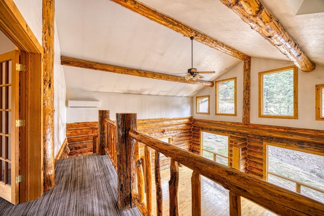 corridor with rustic walls, an upstairs landing, lofted ceiling with beams, and a wall mounted AC