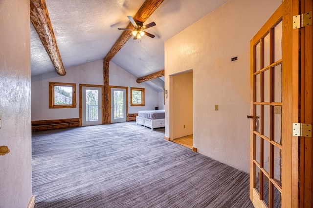 interior space featuring a textured ceiling, carpet, ceiling fan, lofted ceiling with beams, and a textured wall