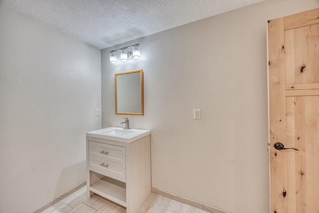 bathroom featuring vanity, a textured ceiling, and baseboards