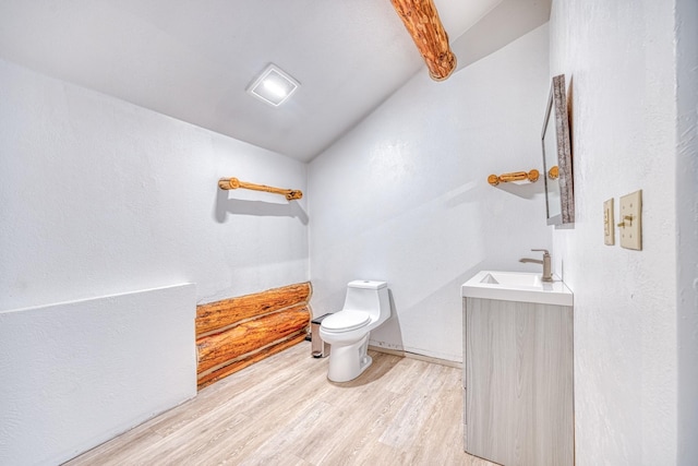 bathroom with lofted ceiling, vanity, toilet, and wood finished floors